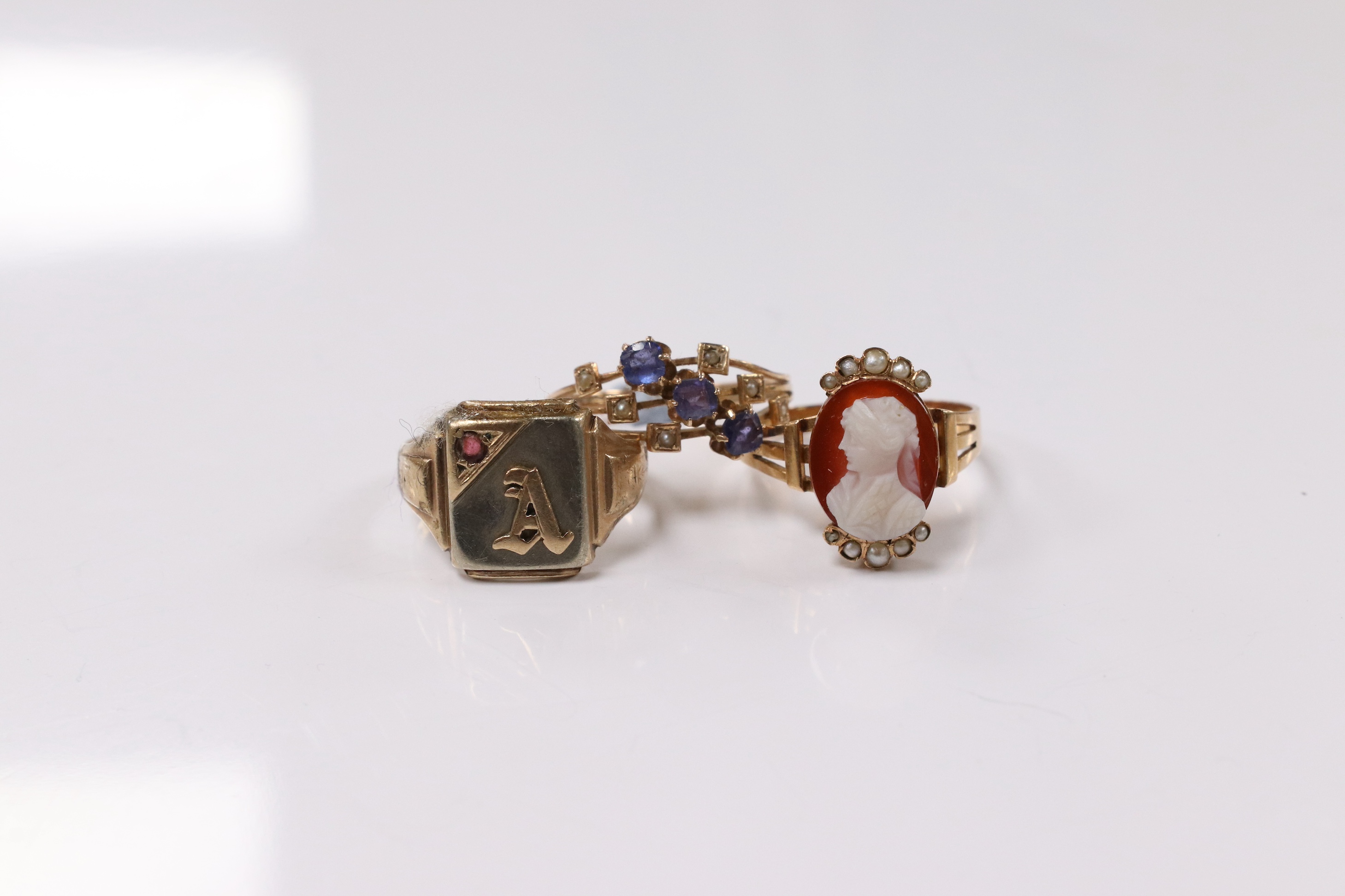 A 10k and gem set initial ring, a continental yellow metal and gem set ring and an early 20th century yellow metal, hardstone cameo and seed pearl set ring, size P, gross weight 8.2 grams. Condition - poor to fair